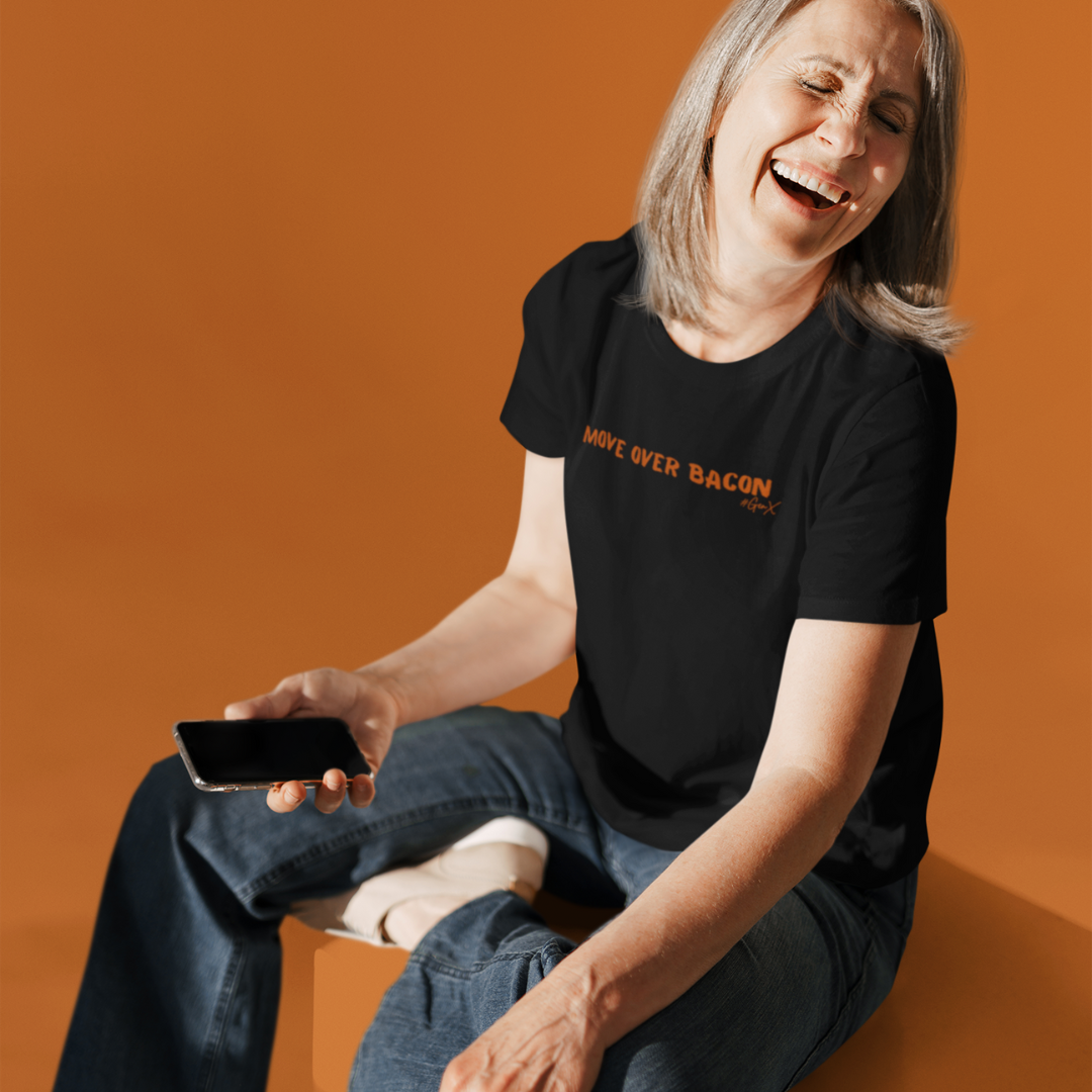 Woman sitting and laughing wearing black unisex short sleeve t-shirt 'Move Over Bacon' design on front with orange font